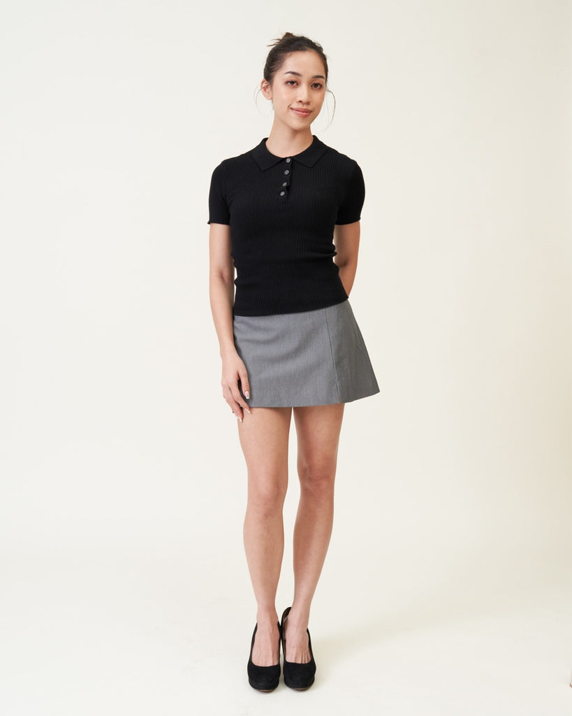 Woman wearing a black top and gray skirt on a white background