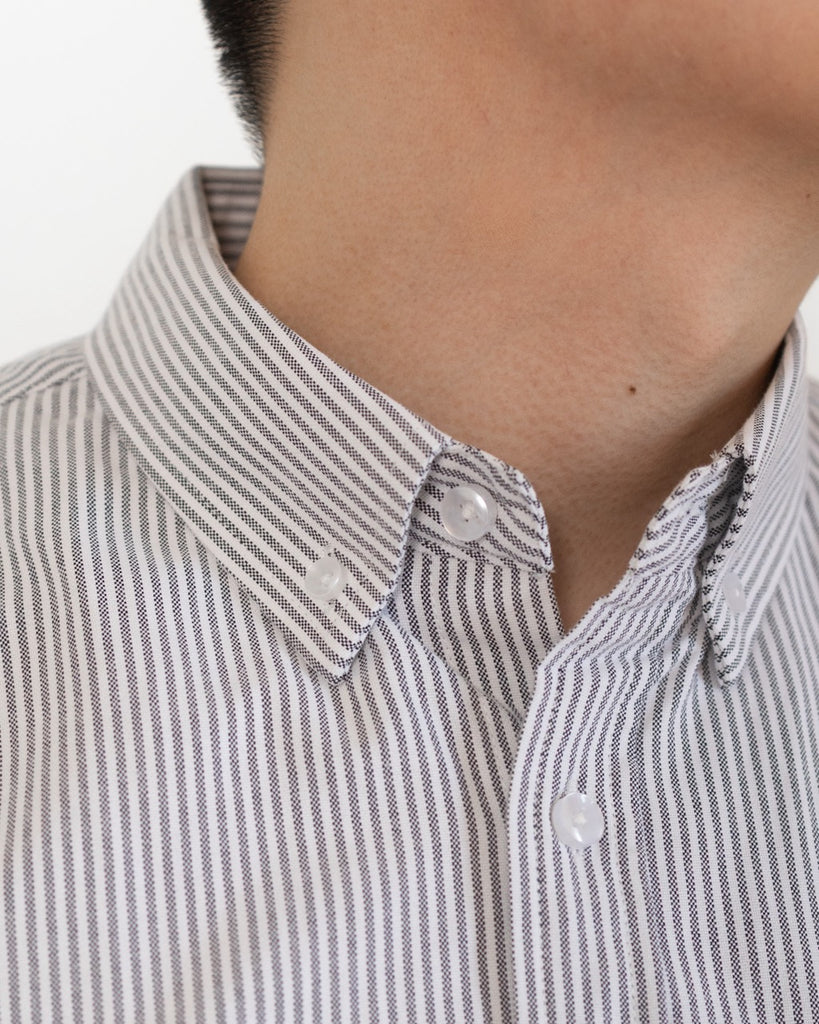 Close-up of a person wearing a gray and white striped shirt with a plain background
